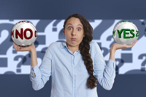 Woman with a puzzled look holding 'yes' and 'no' balls in her hands